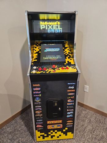 A small arcade machine with a black background and yellow and black pixelated design.
